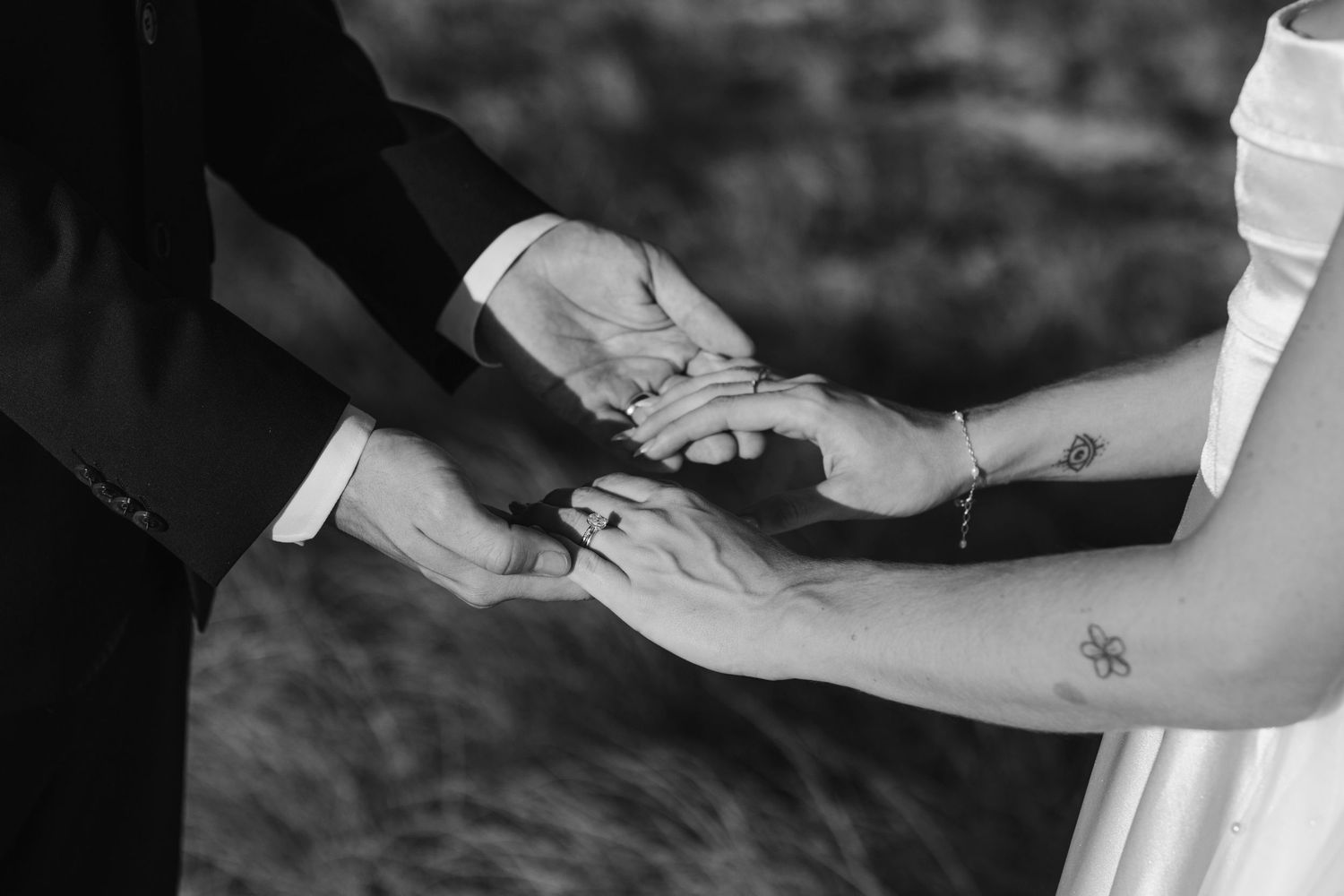 Black and white close-up of hands exchanging rings during wedding ceremony.beach wedding currumbin surf club wedding