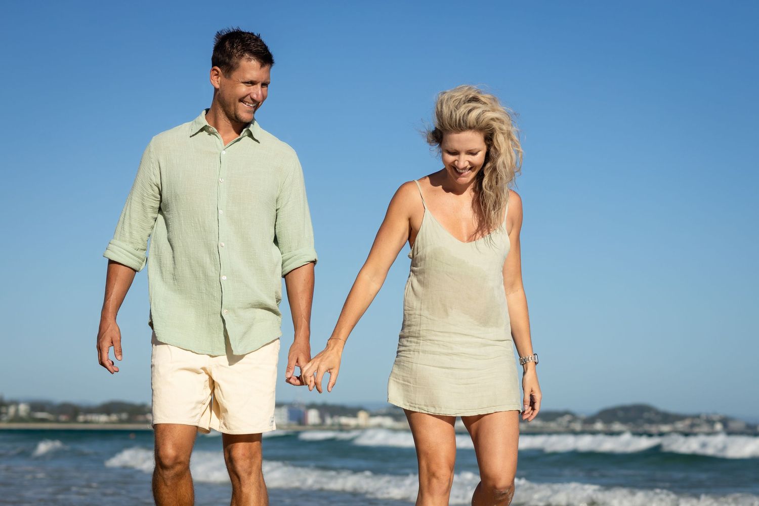 Couple walking together on a sunny beach wearing casual summer clothing.Family photography Kirra beach Gold Coast
