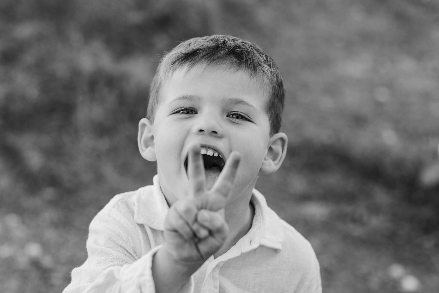 Child in white shirt makes expressive face in black and white close-up portrait.Cabarita headland