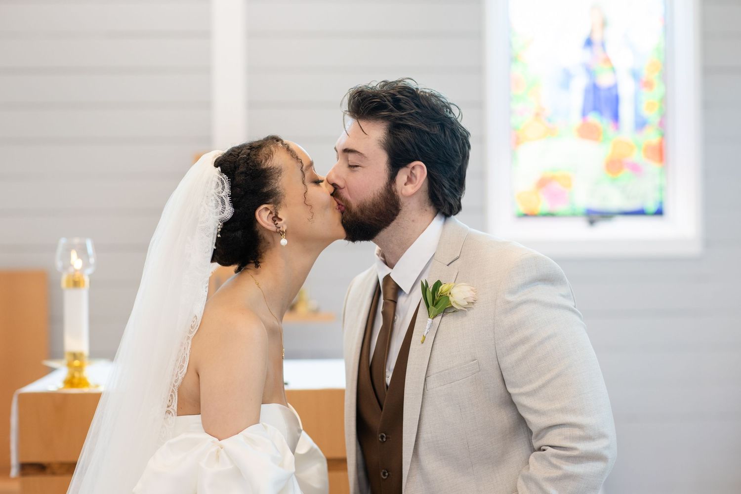Intimate wedding ceremony moment in a minimalist white chapel interior.
