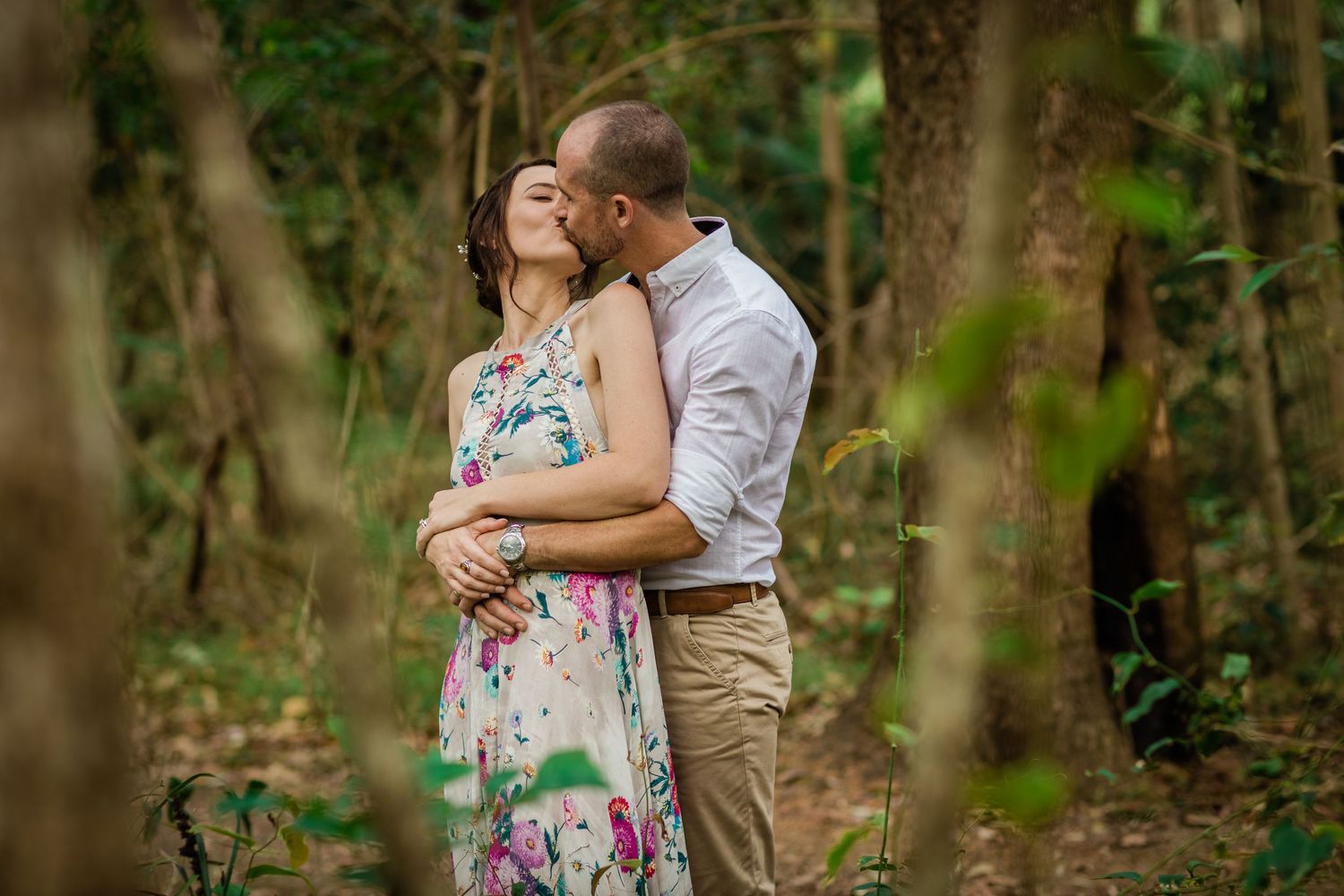 Two people embrace in a romantic forest setting surrounded by green foliage.Gold Coast elopement photographer