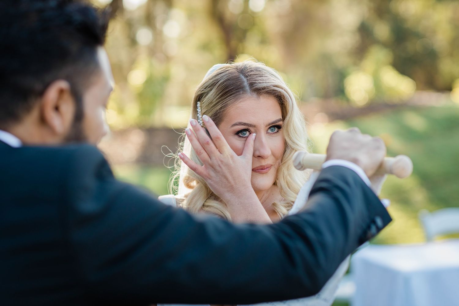 A couple embraces outdoors during an emotional moment in a natural setting with sunlit trees in the background. Surfers Paradise Golf Club w