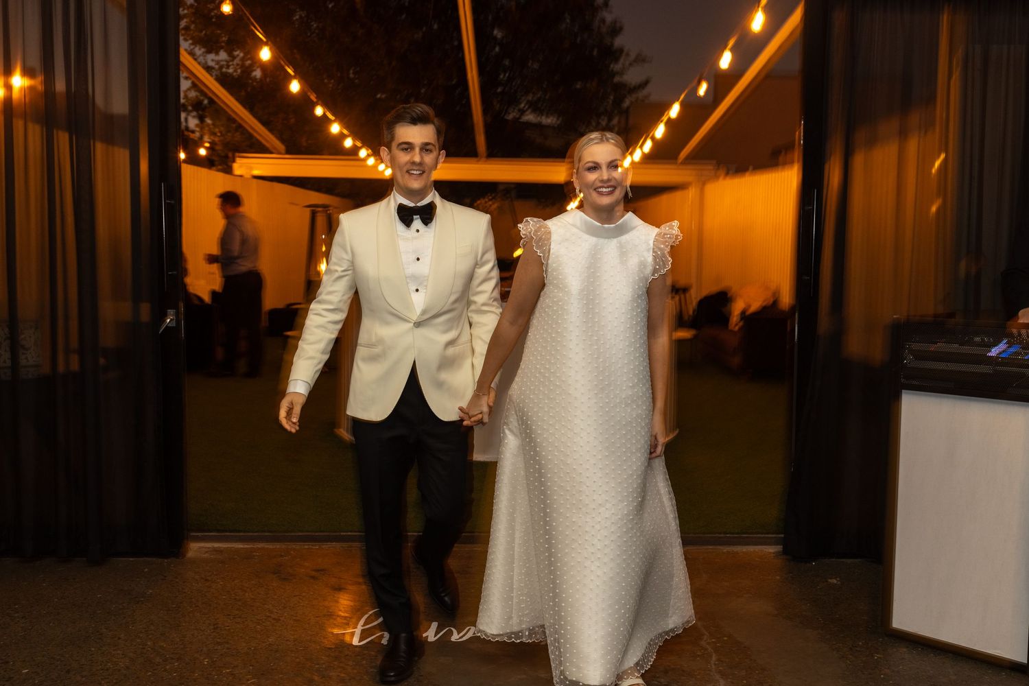 Guests dance and celebrate at an elegant wedding reception with warm lighting and formal attire.