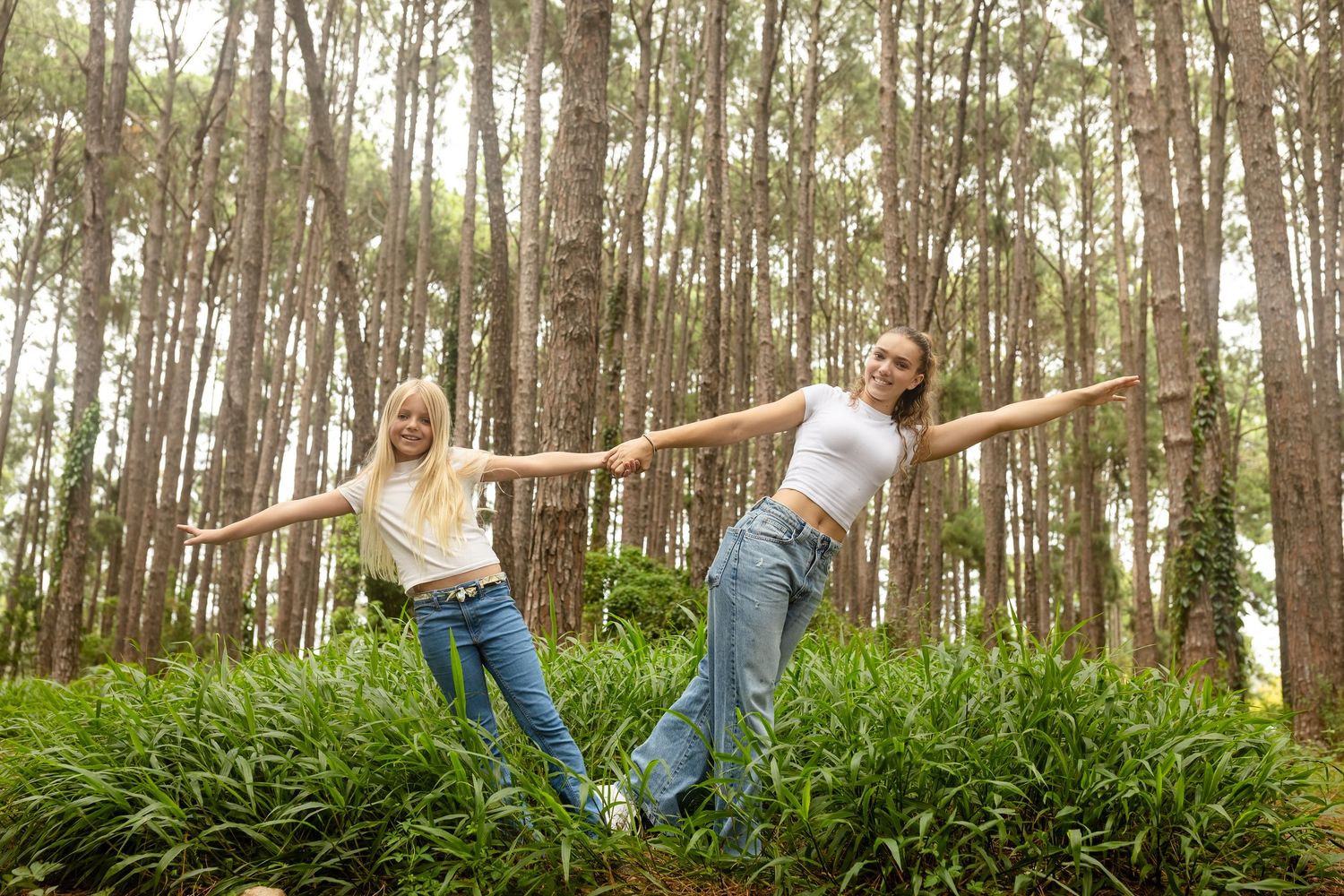 People walking through a lush green forest with arms outstretched in joy.Pizzey park family photos. Gold Coast