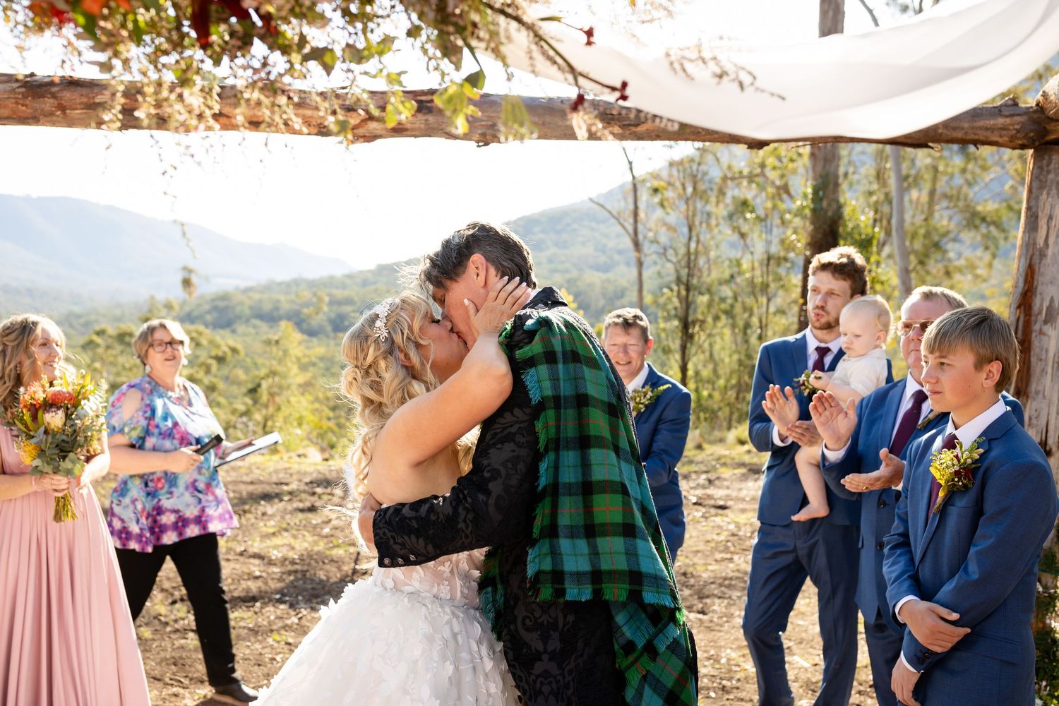 Wedding party poses for photos with mountain range and forest backdrop during outdoor celebration.Gold Coast wedding photographer