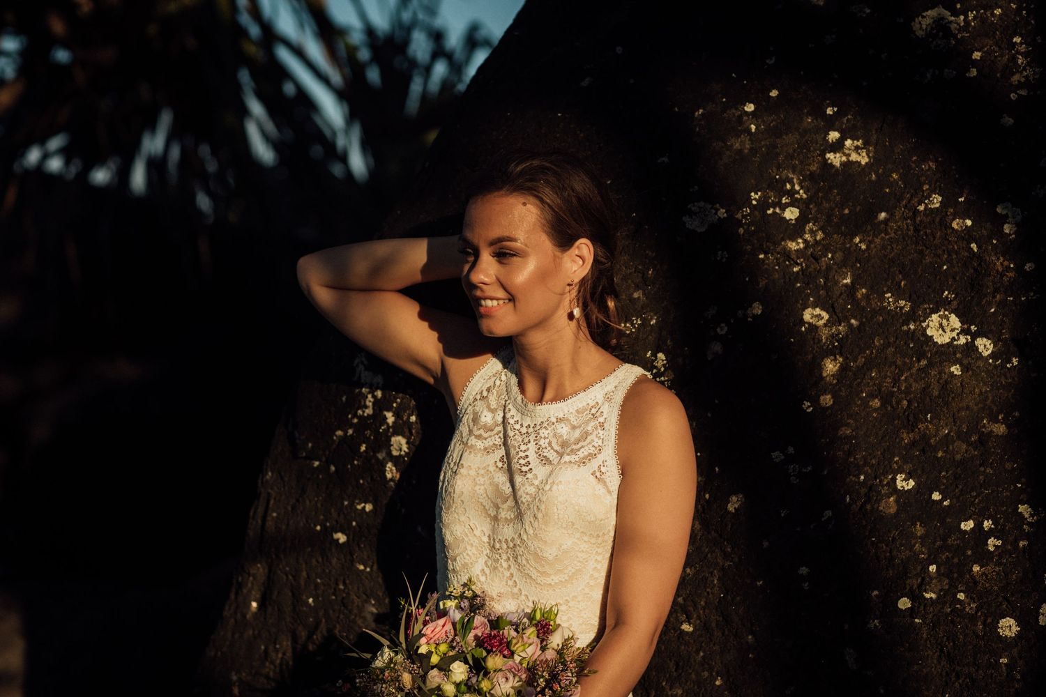 A bride in lace dress holds bouquet during golden hour sunset.Gold Coast beach wedding photography. Froggies beach