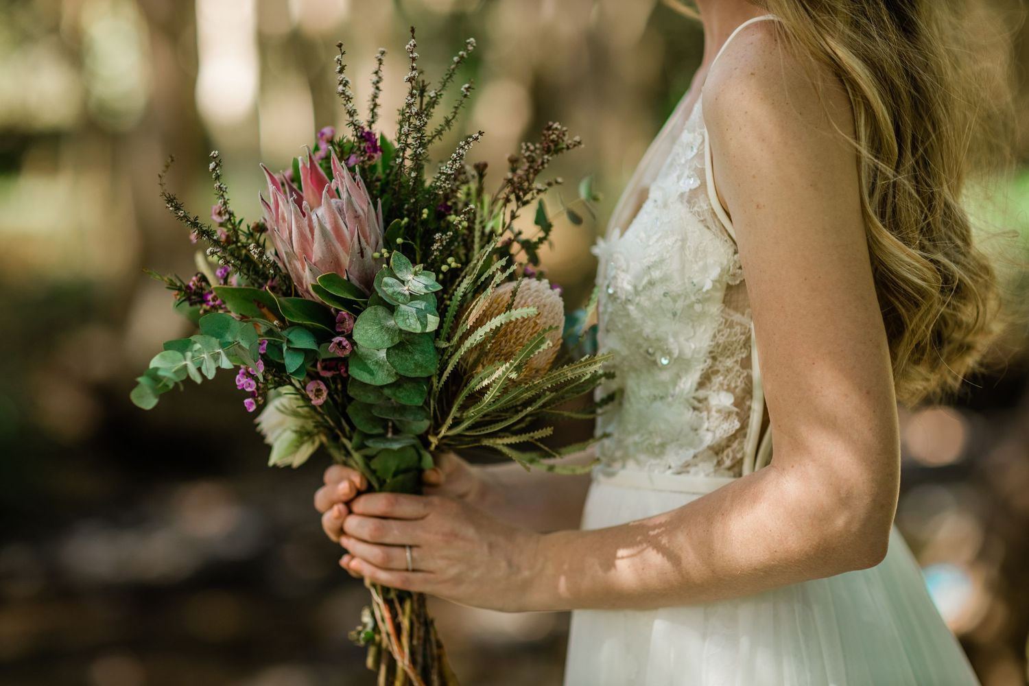 Elegant bridal details featuring a white lace dress and natural bouquet against garden backdrop.Gold Coast beach wedding photography