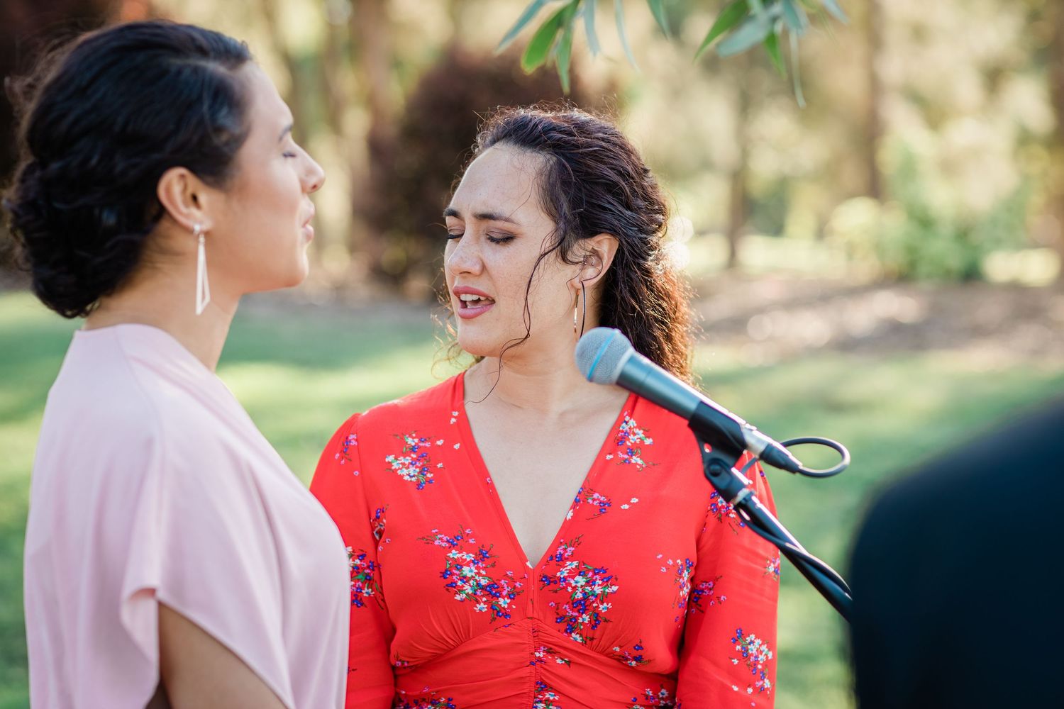 Guests in colorful floral dresses sharing a laugh during the wedding ceremony.
