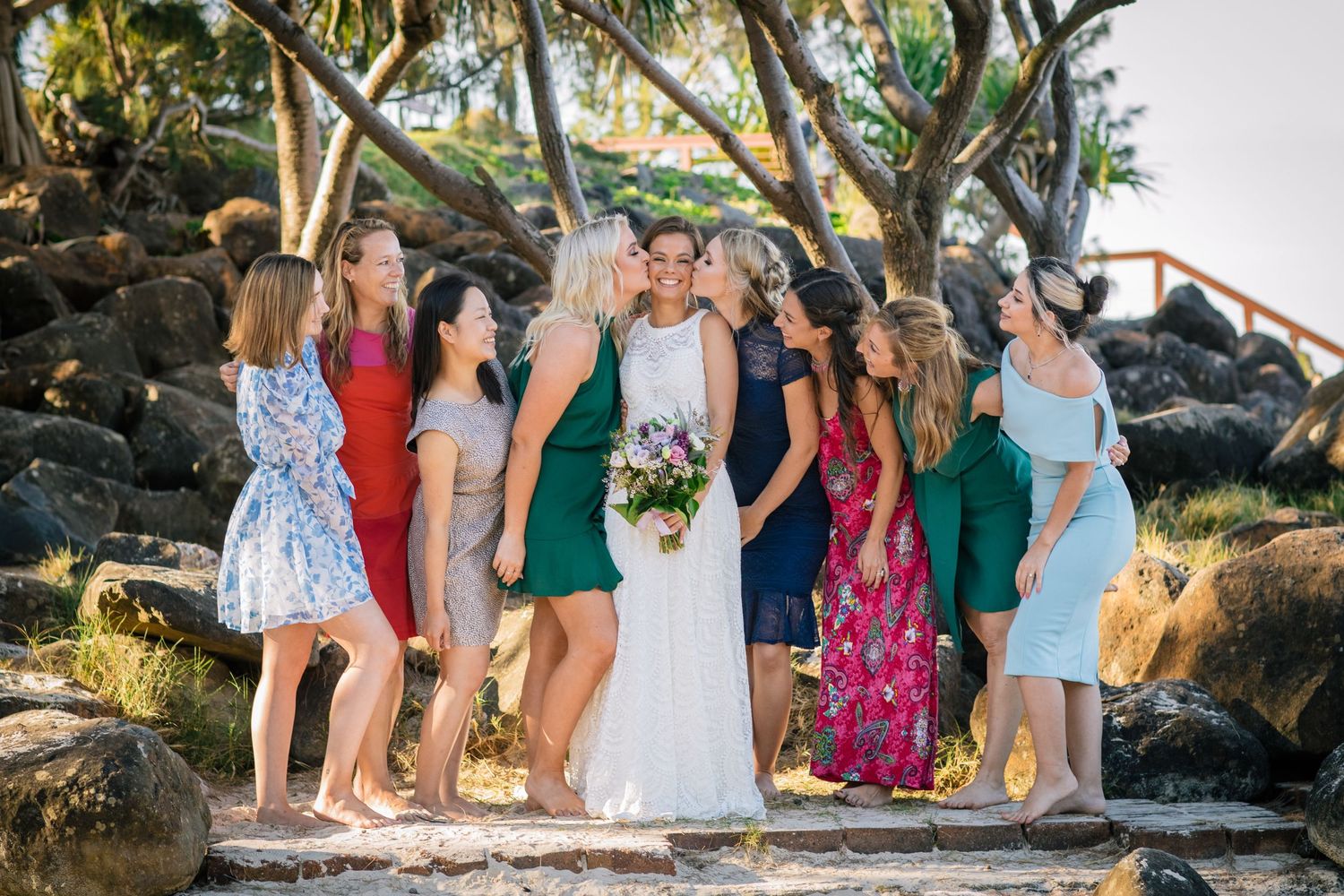 Wedding party gathers on tropical beach path surrounded by palm trees and volcanic Gold Coast beach wedding photography. Froggies beacrocks.