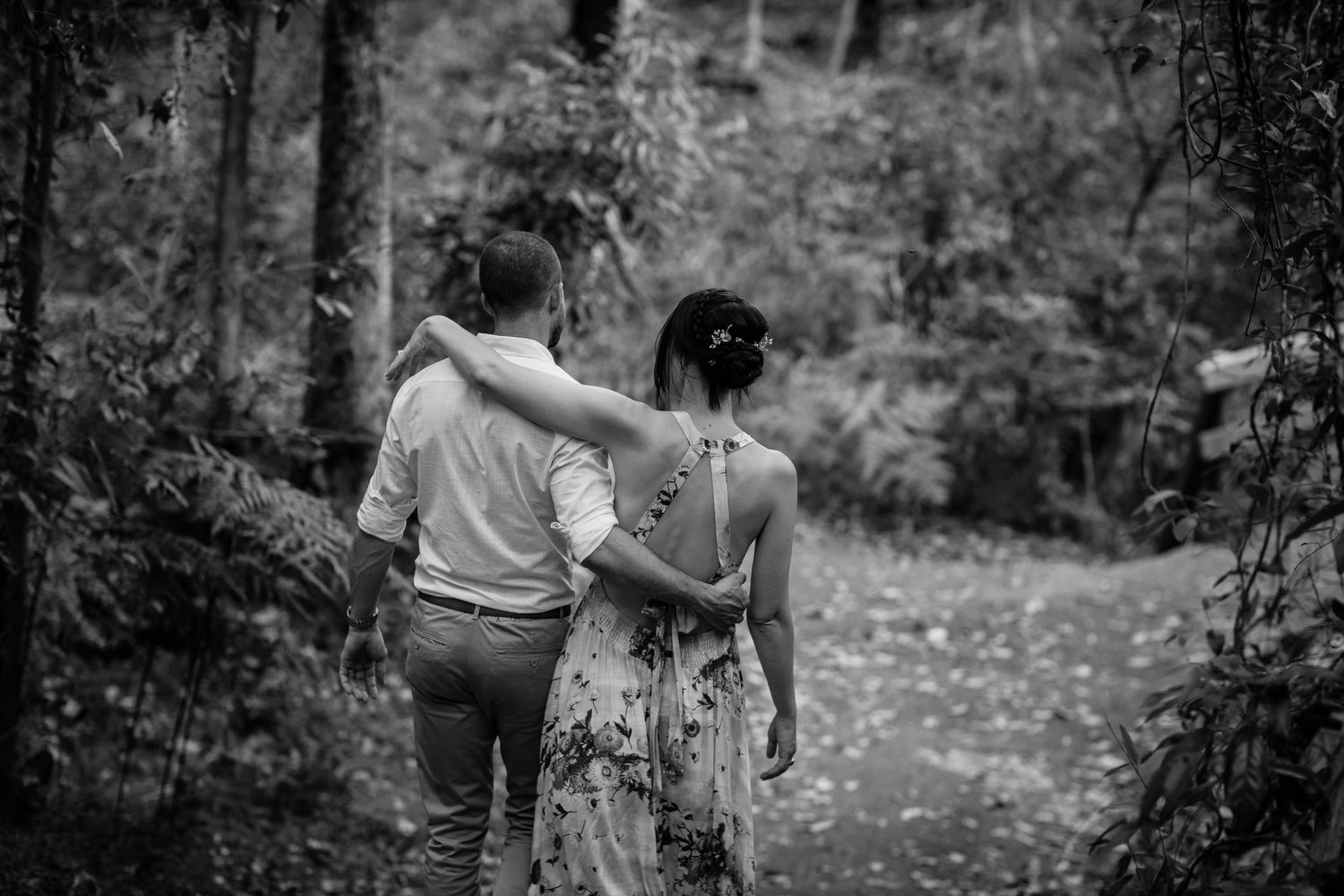 A black and white photo shows two people embracing in a serene forest environment.Gold Coast elopement photographer