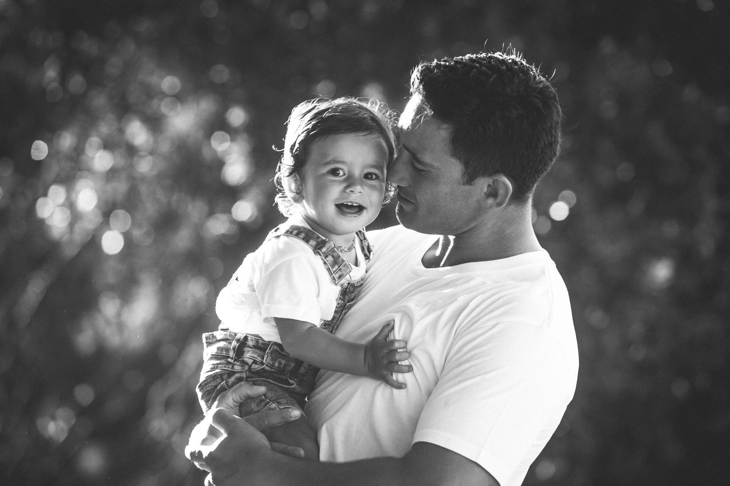 Black and white portrait capturing intimate family moment outdoors.