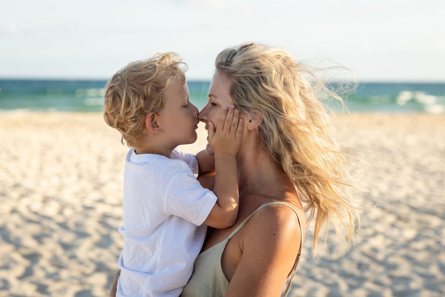 Playful interaction between family members on a sunny beach with golden light.Gold Coast candid family photographer.