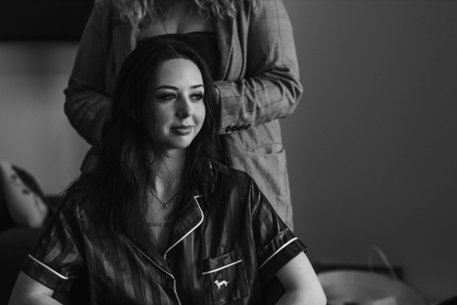Black and white image of person getting ready in casual attire during wedding preparations.