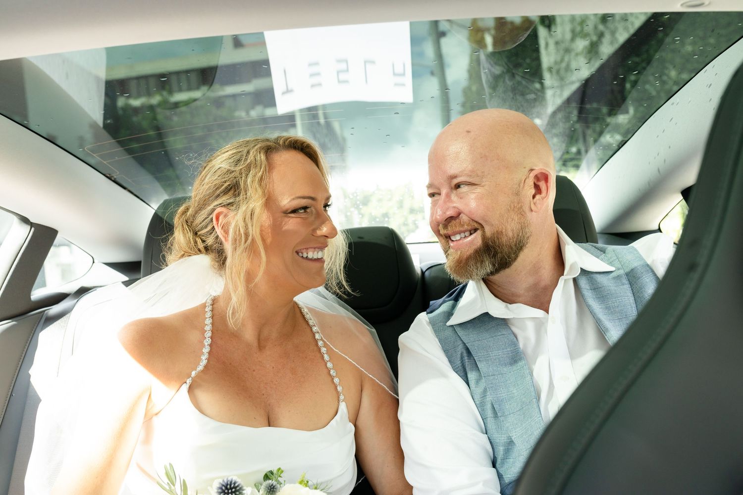 Couple shares joyful moment together in car after wedding ceremony at iris rooftop hotel in brisbane.