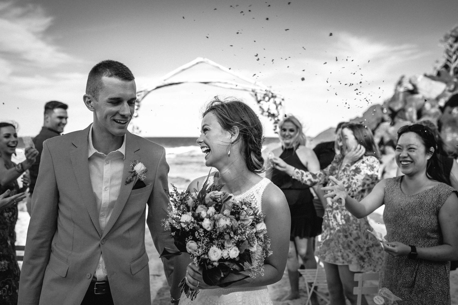 Black and white wedding celebration with confetti flying in the air.Gold Coast beach wedding photography. Froggies beach