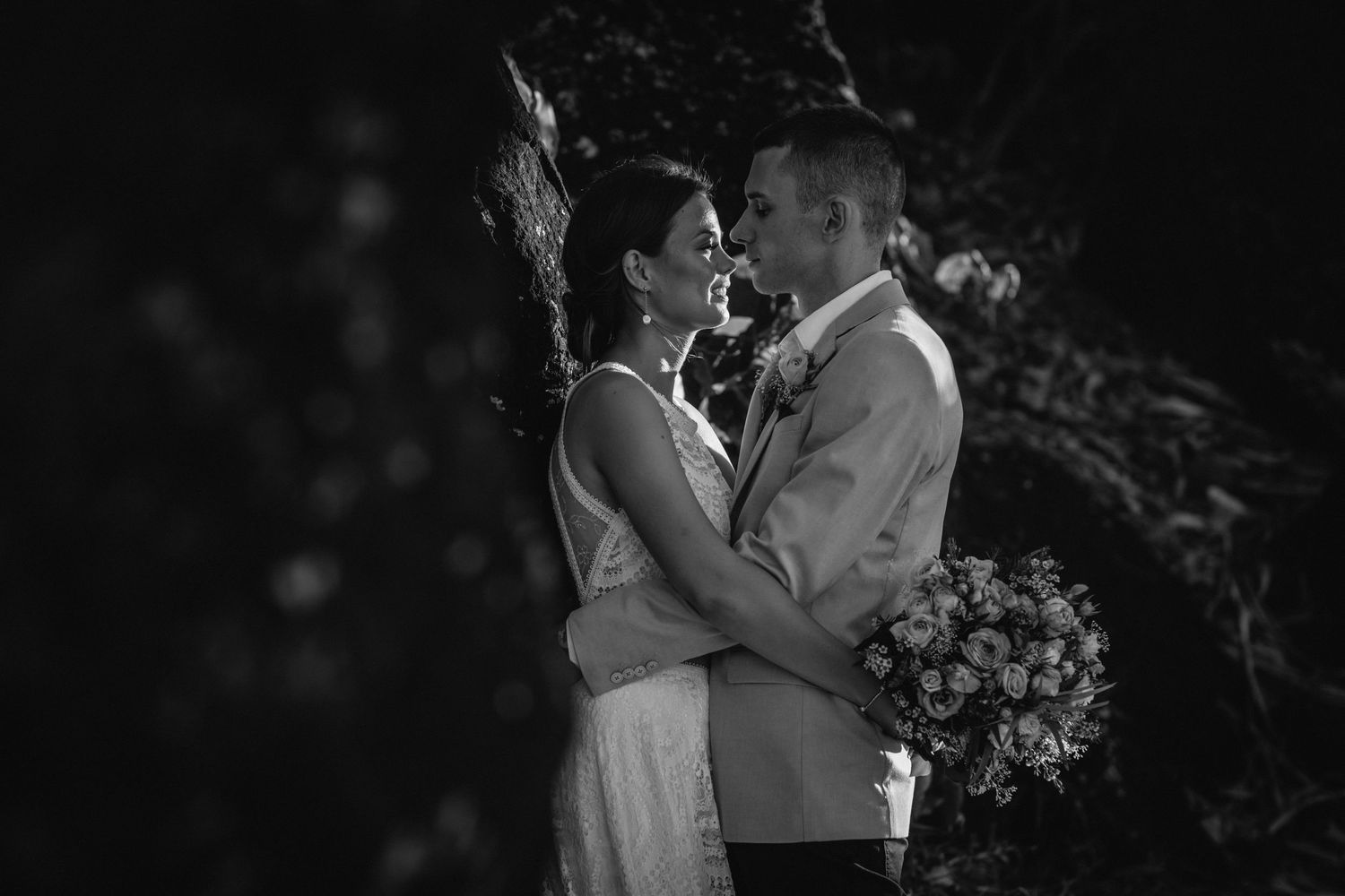 A romantic black and white wedding portrait of a couple embracing outdoors with flowers.Gold Coast beach wedding photography. Froggies beach