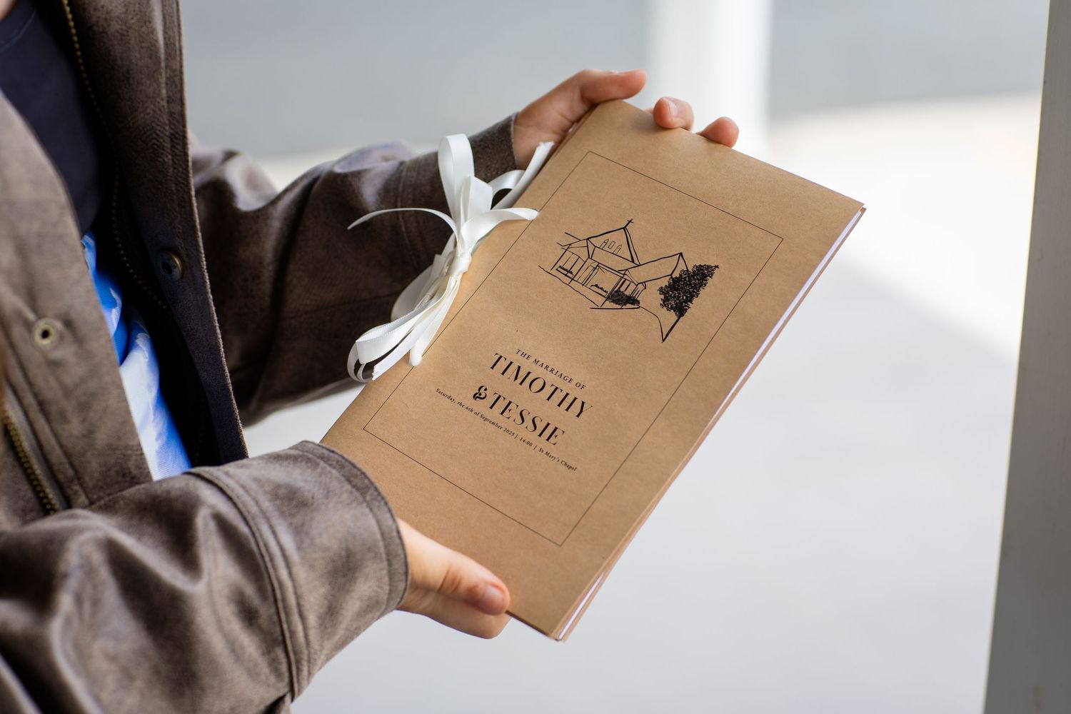 Hand holding a brown kraft paper journal or notebook in natural light.