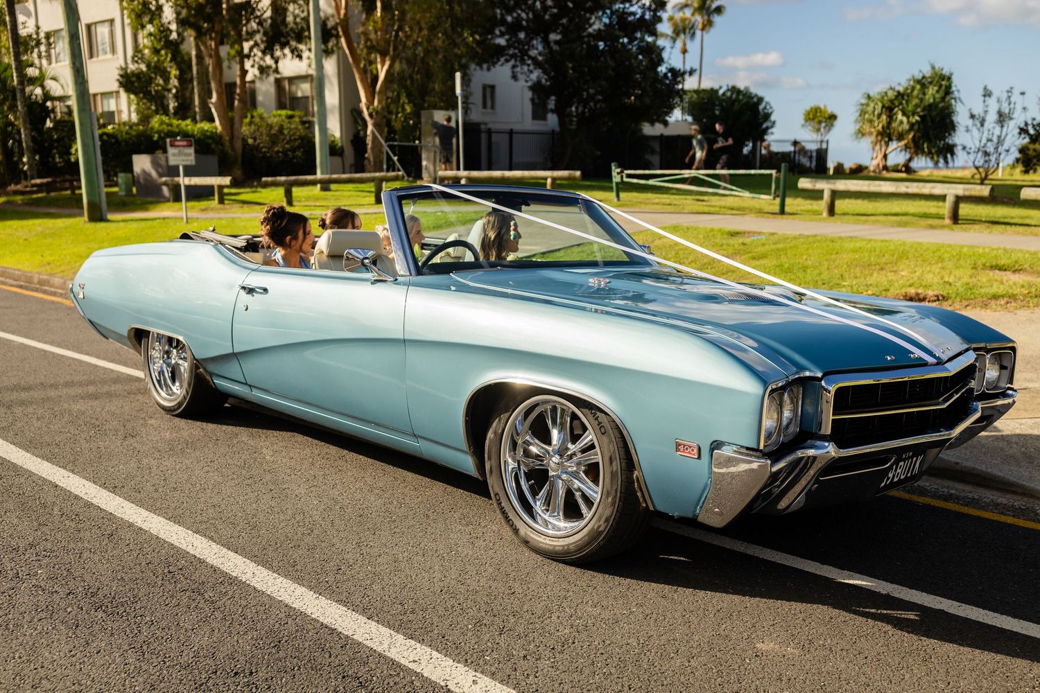Vintage light blue car photographed from multiple angles at outdoor wedding venue.