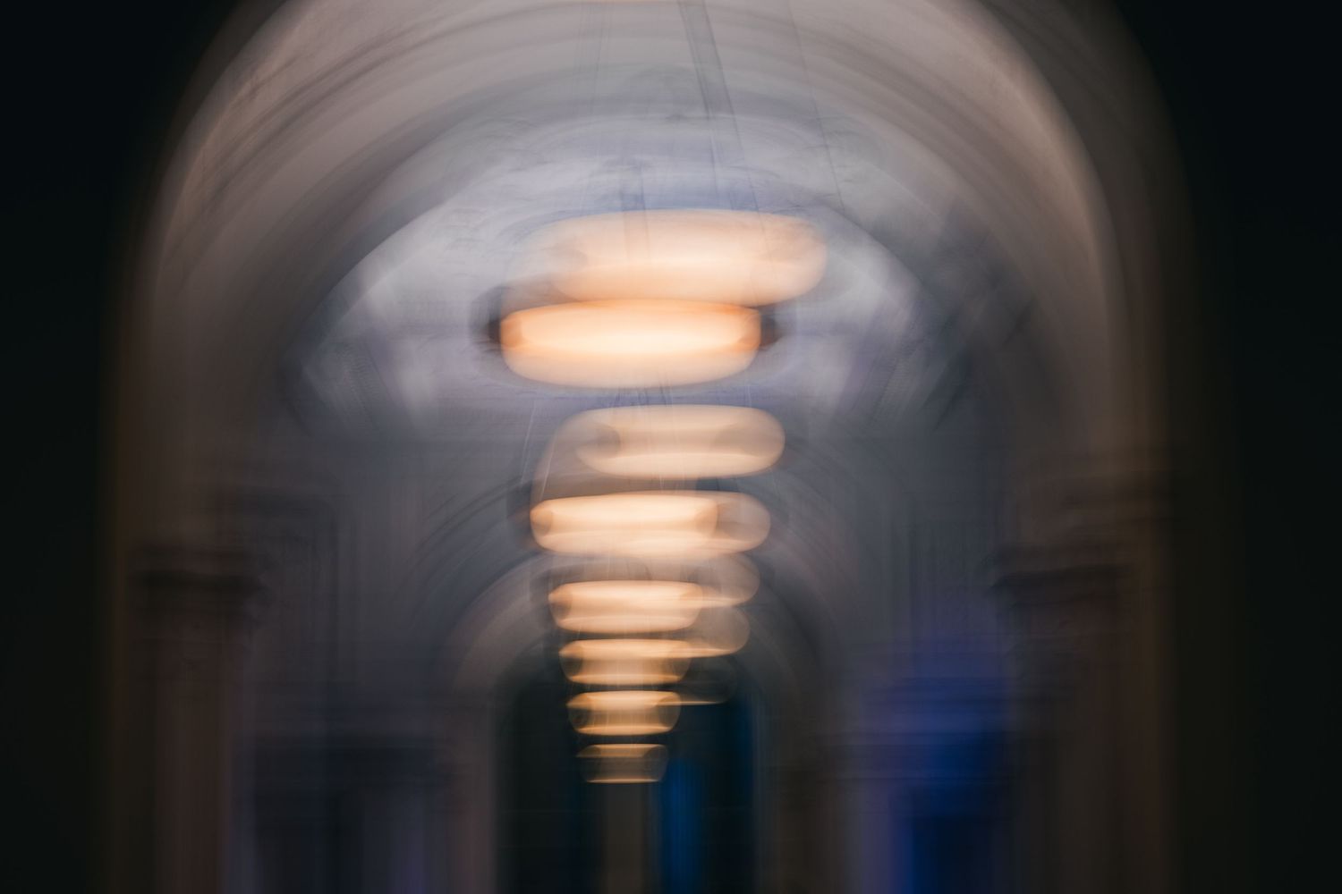 Abstract architectural photo of a hallway ceiling with blurred lighting creating a tunnel effect.