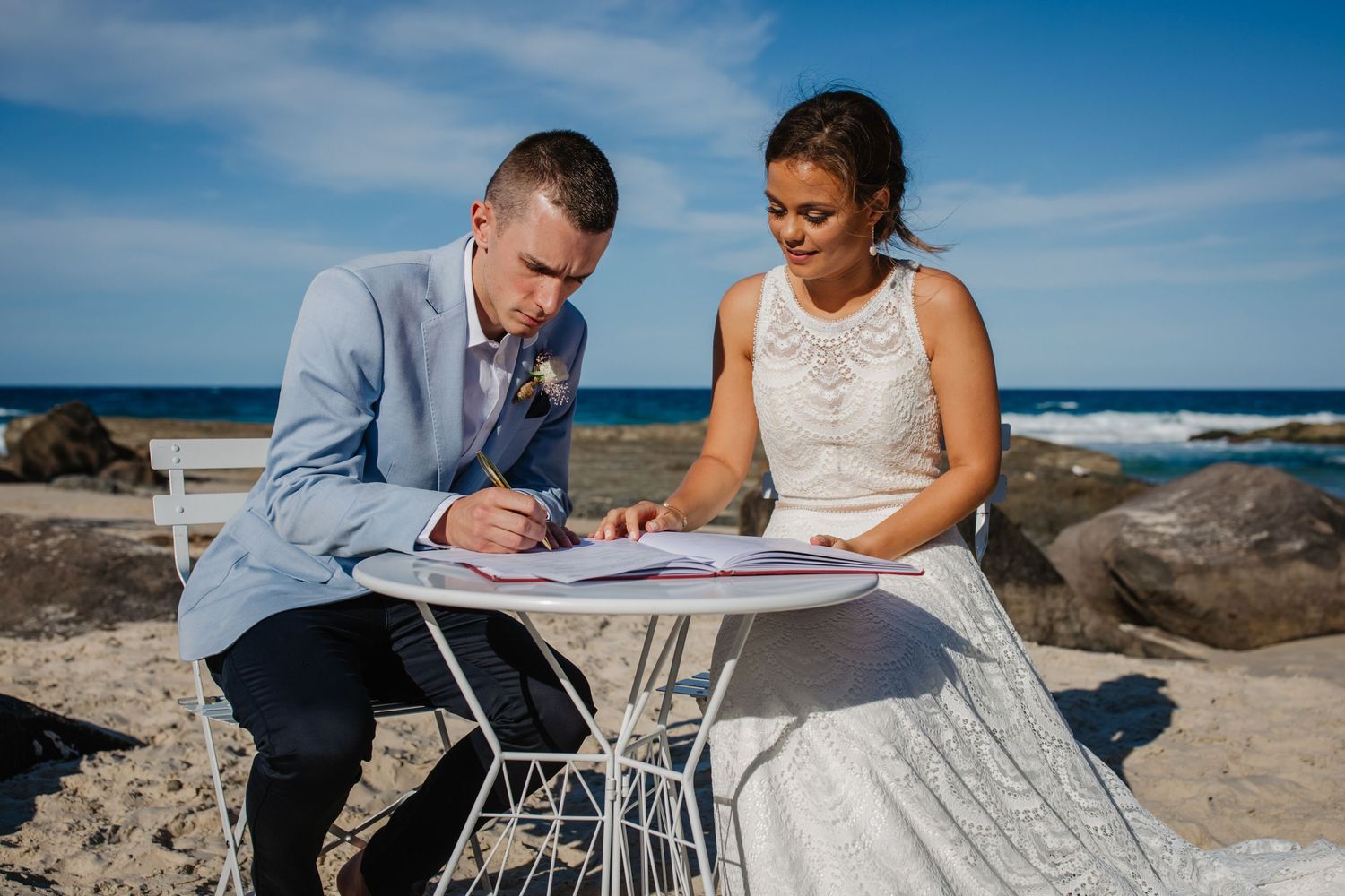 Couple signing marriage documents at outdoor beach ceremony with ocean views.Gold Coast beach wedding photography. Froggies beach