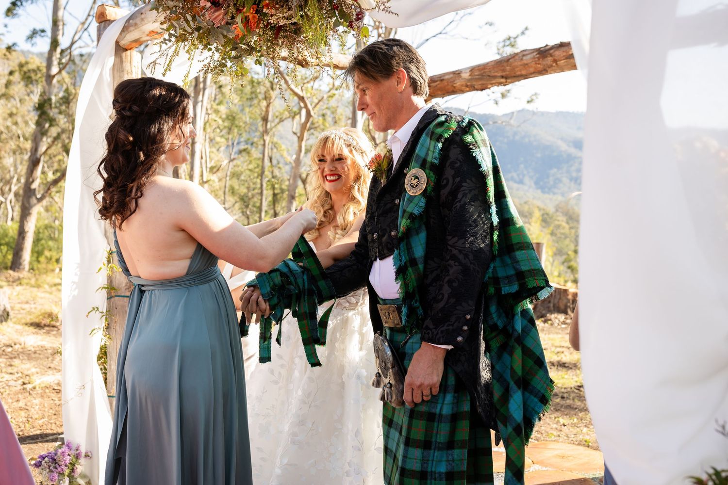 Wedding guests in formal attire and traditional Scottish kilts gather at scenic mountain venue.Gold Coast wedding photographer