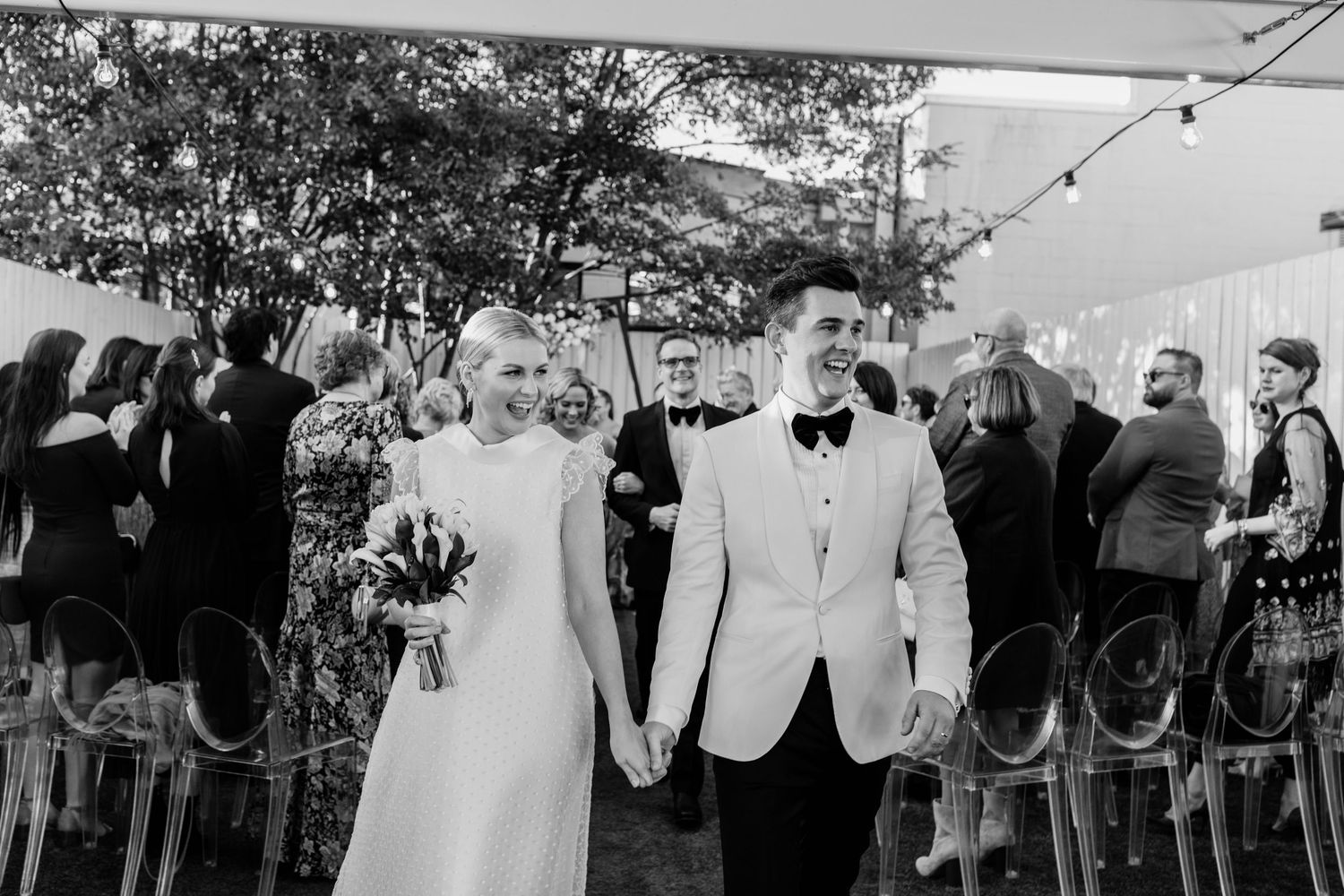 Wedding celebration under string lights with guests gathered outdoors.The refinery wedding venue. Brisbane.