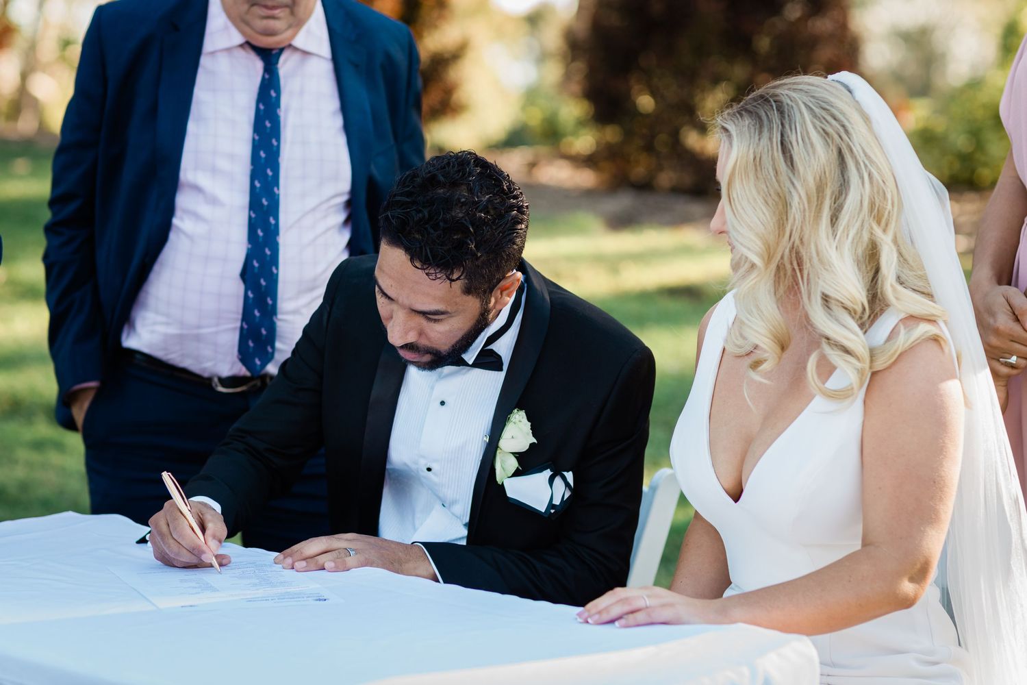 A couple signs their marriage certificate during their outdoor garden wedding ceremony.