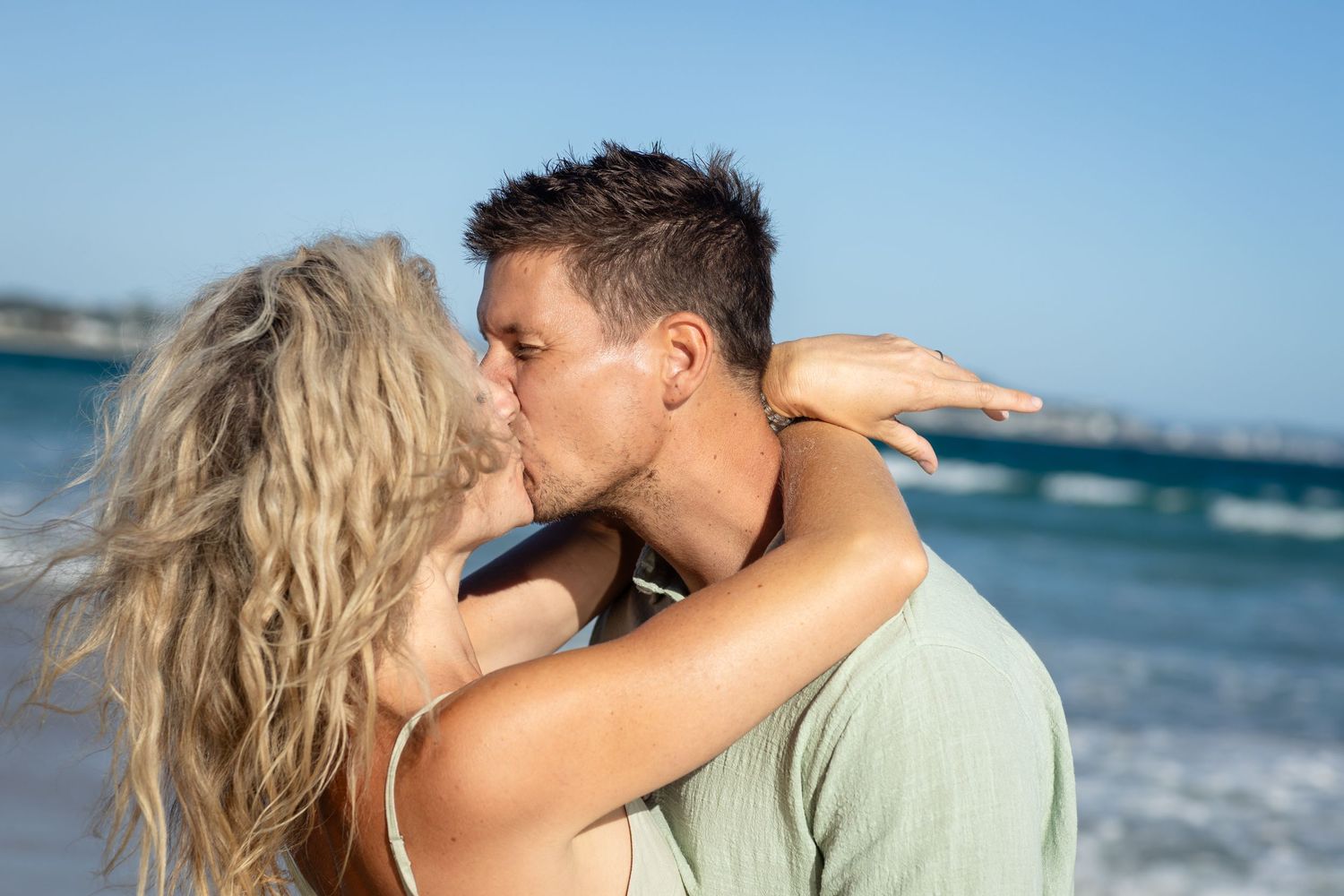 A romantic beach scene with ocean waves and blue sky in the background.Family photography Kirra beach Gold Coast. Gold Coast candid family p