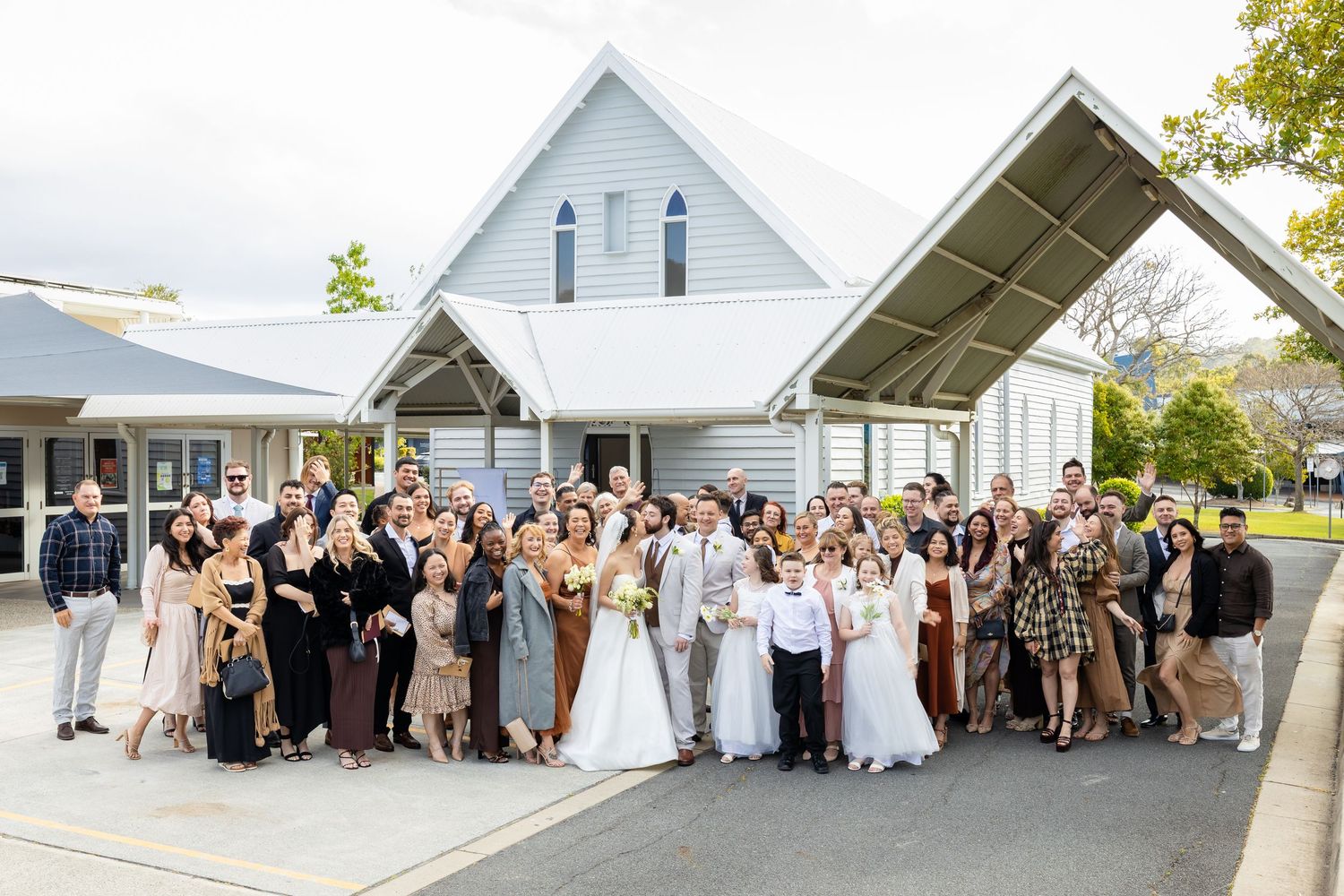 Large group of wedding guests gathered outside a white building for a celebratory photo.The barrow restaurant mount Nathan wedding
