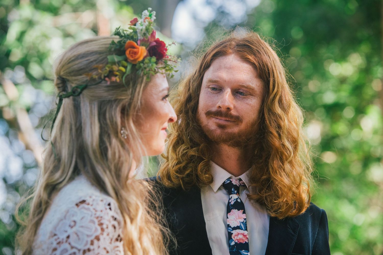 A couple shares an intimate moment in a lush garden setting wearing bohemian wedding attire.
