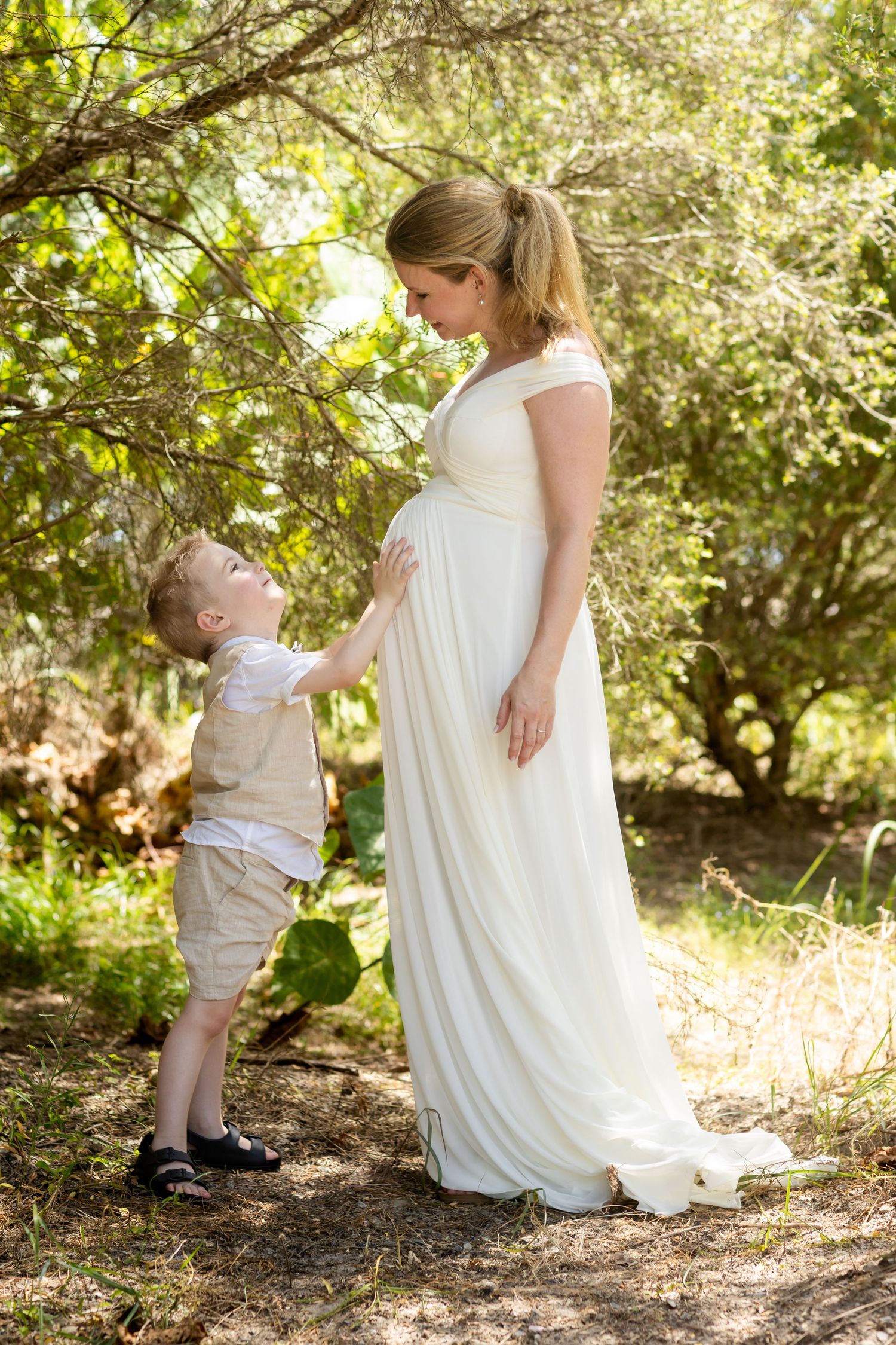 Sweet moments between a bride in white dress and small child in garden setting.candid wedding photography Gold Coast