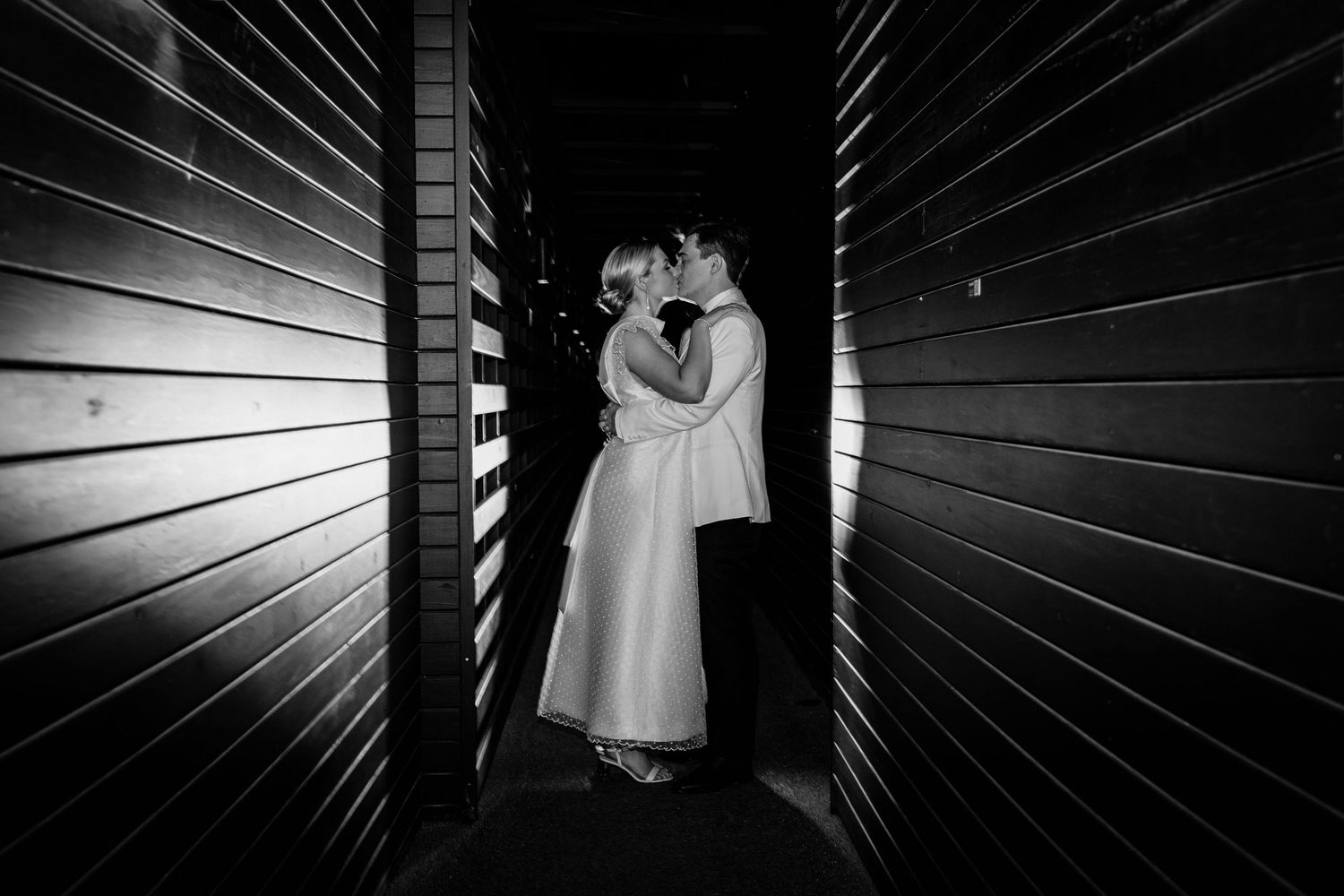 Dramatic black and white wedding photo with artistic lighting and shadows.