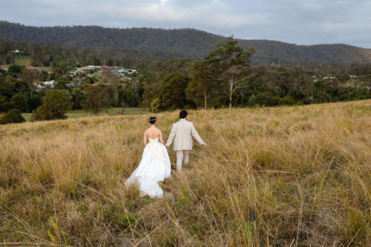 A scenic wedding photo session in a grassy field with mountains and trees in the background.The barrow restaurant mount Nathan wedding