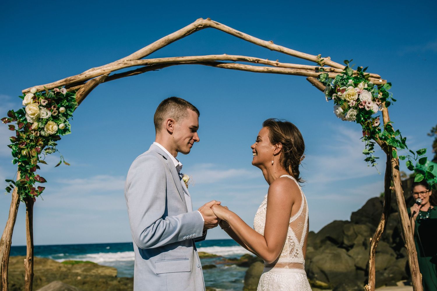 Beachside wedding ceremony under wooden arch with floral decorations.Gold Coast beach wedding photography. Froggies beach