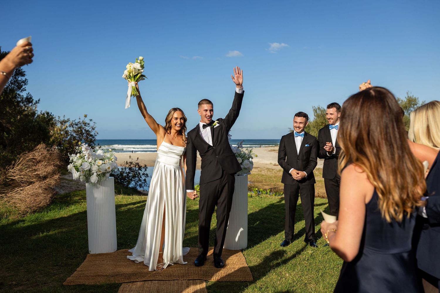 Wedding party celebrates on a scenic coastal cliff overlooking the ocean.beach wedding currumbin surf club wedding