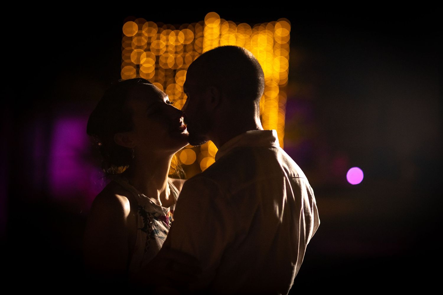 Silhouettes of people against warm glowing lights at night.