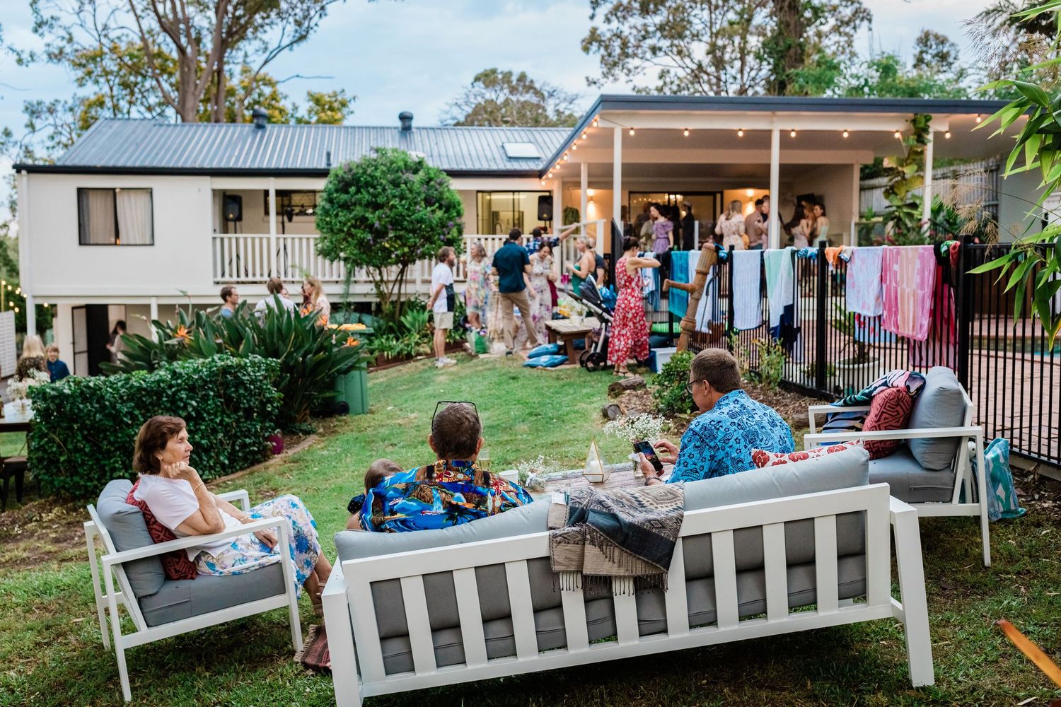 Group relaxing on white benches during an outdoor social event.Gold Coast elopement photographer