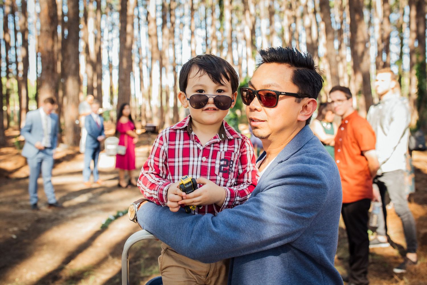 Guests wearing sunglasses share a moment during an outdoor forest wedding celebration.