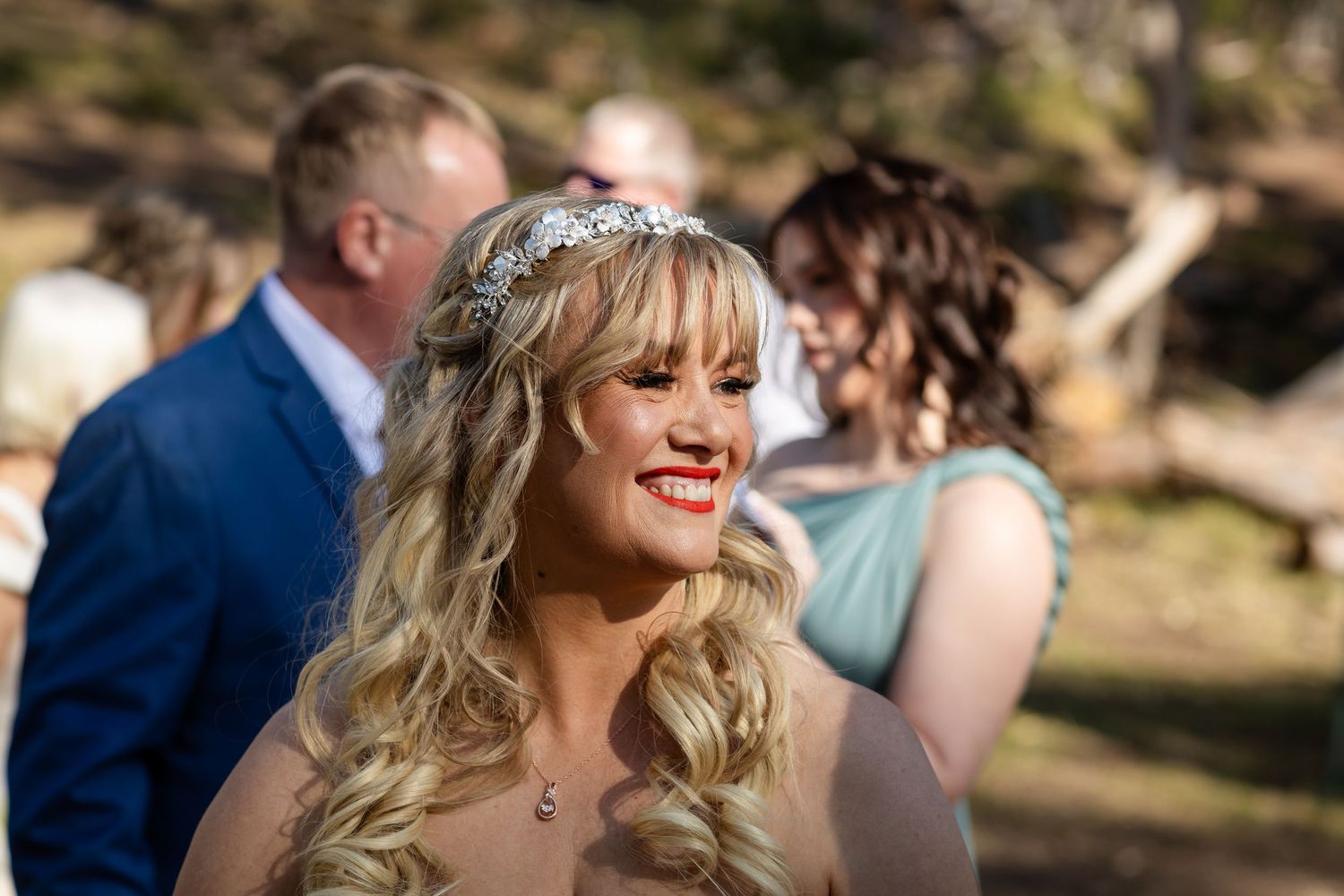 Wedding celebration with guests gathered under trees in a scenic mountain landscape.