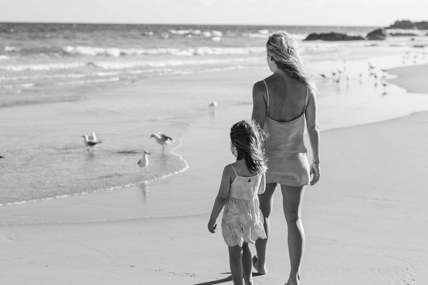 Silhouettes walking together along a sandy beach at sunset.Gold Coast candid family photographer.