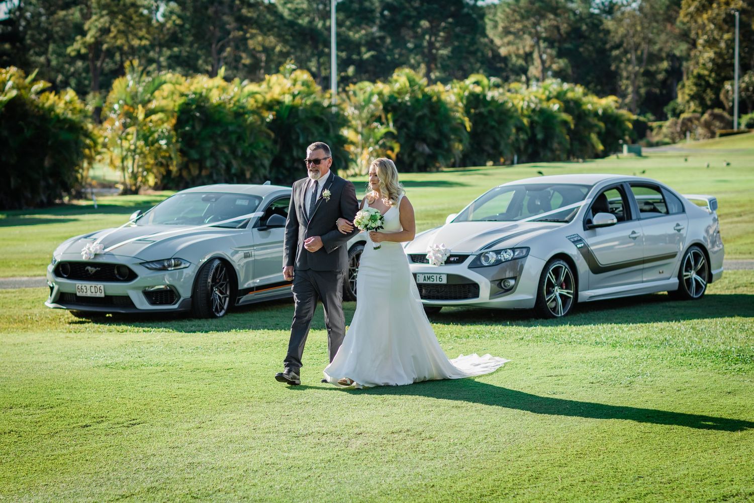 Luxury wedding cars lined up on green grass during outdoor celebration. Surfers Paradise Golf Club wedding.