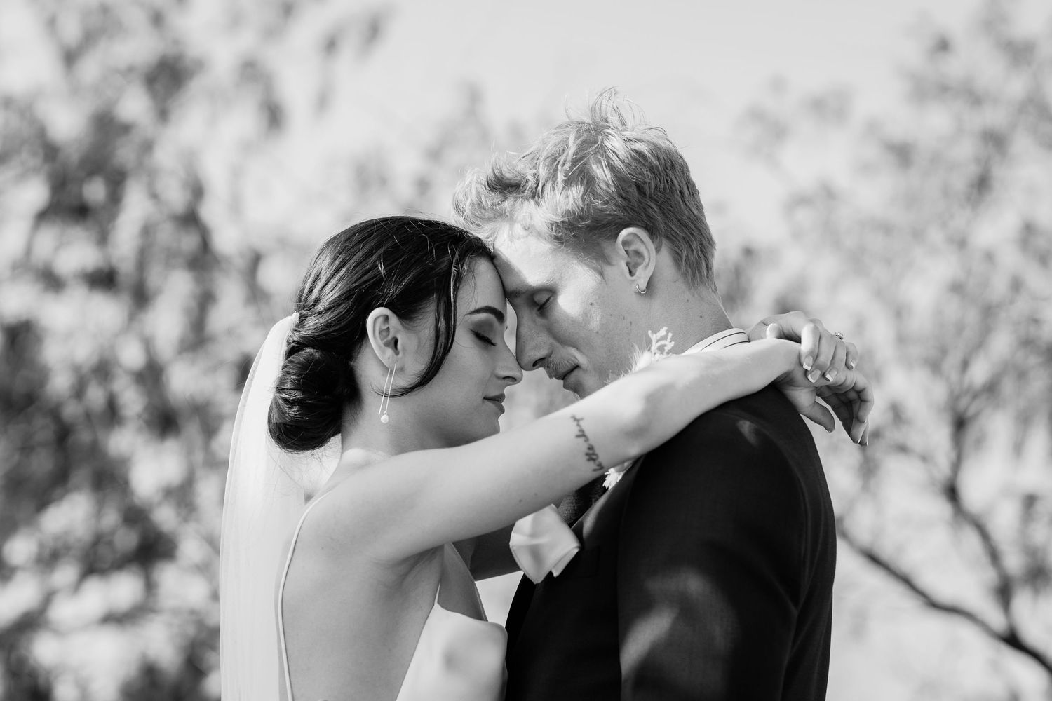 A black and white wedding portrait capturing a tender moment between newlyweds.