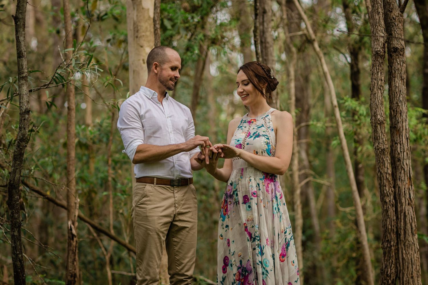 A couple enjoys a romantic moment together in a lush green forest setting.Gold Coast elopement photographer