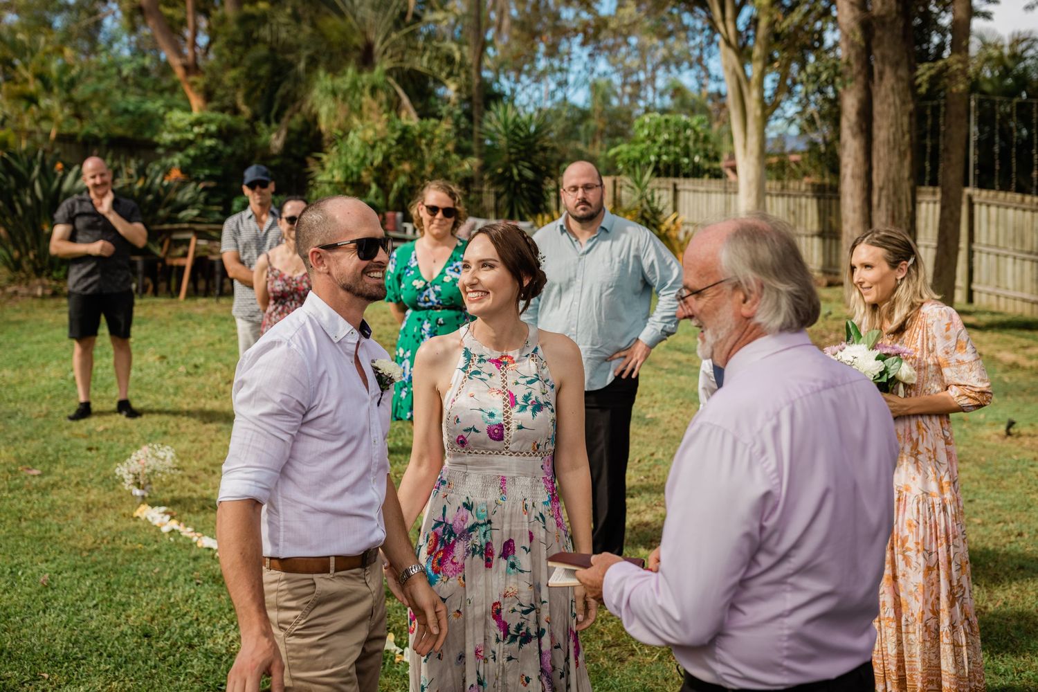 Wedding attendees enjoy conversation in a lush garden setting with natural lighting.