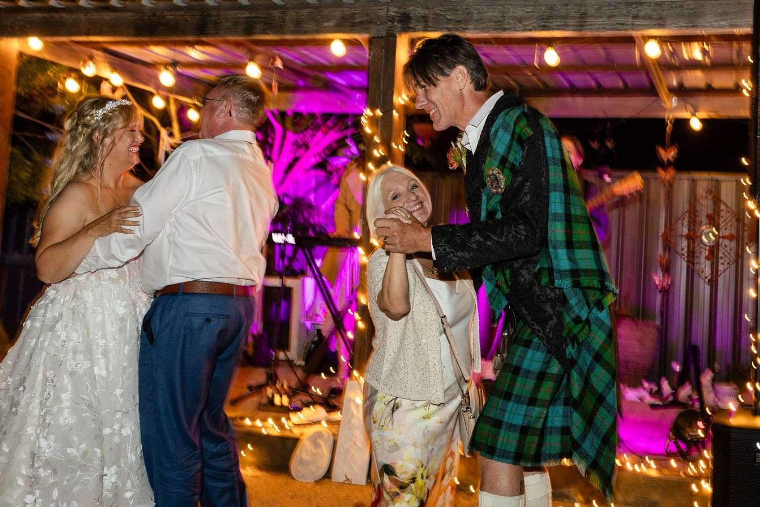 Wedding reception venue with purple uplighting and string lights creating a festive atmosphere.