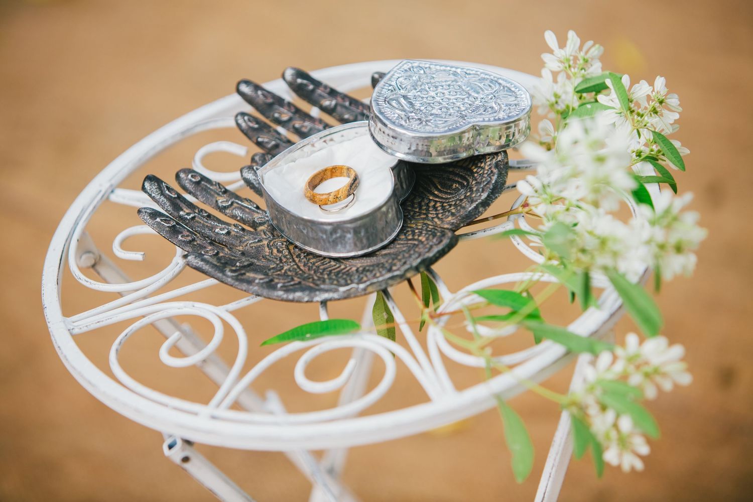 Decorative silver teacups and saucers with delicate white flowers on tan background.
