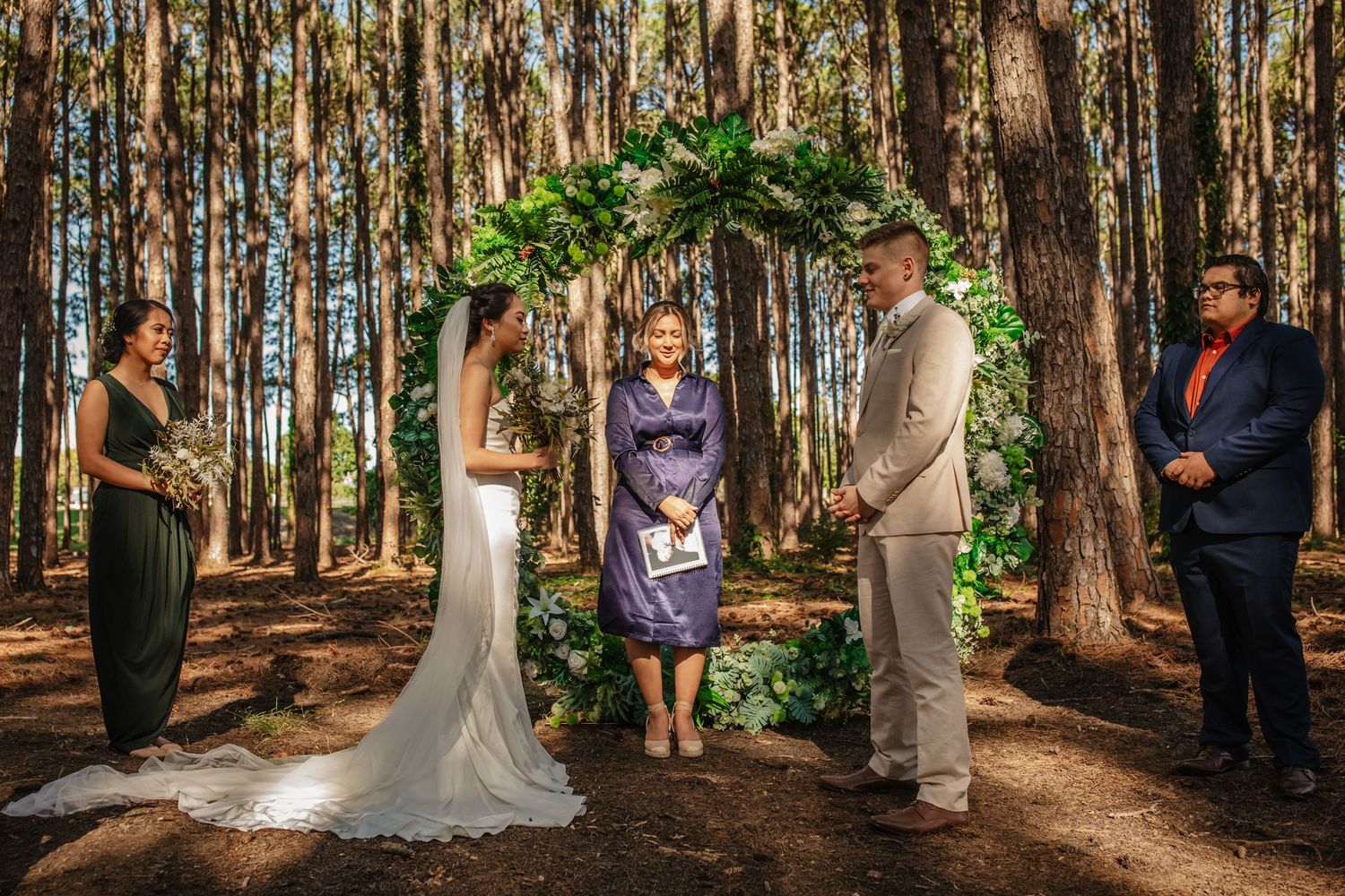 Wedding ceremony takes place in a serene pine forest setting with natural sunlight filtering through.pizzey park wedding Gold Coast