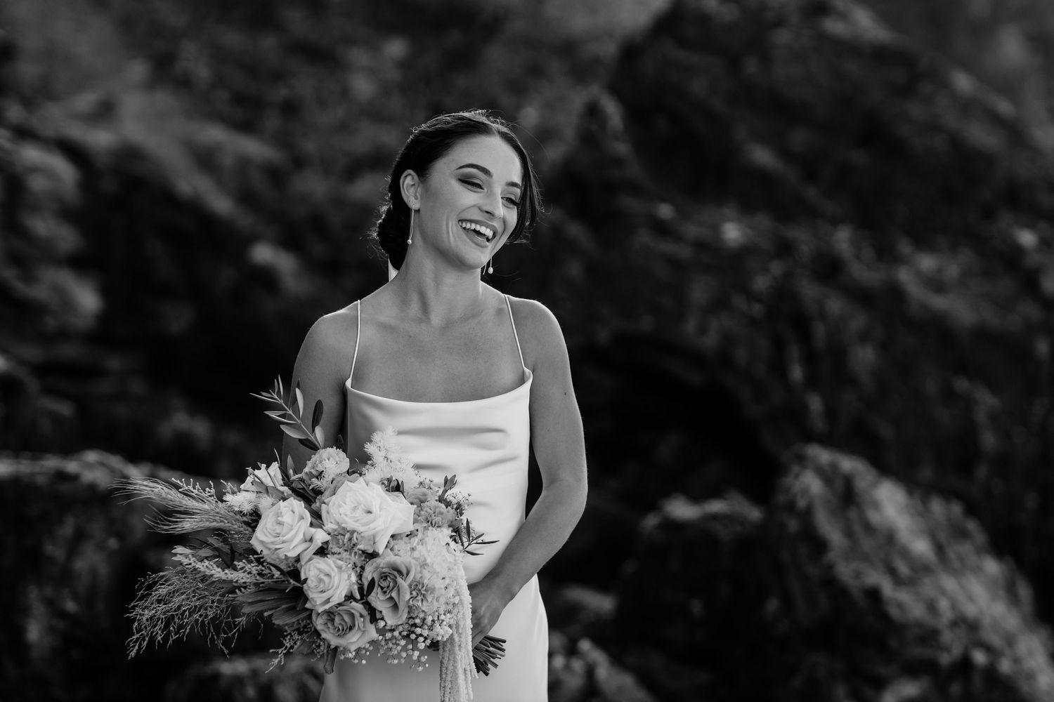Dramatic black and white wedding portraits captured against rocky natural backdrop.
