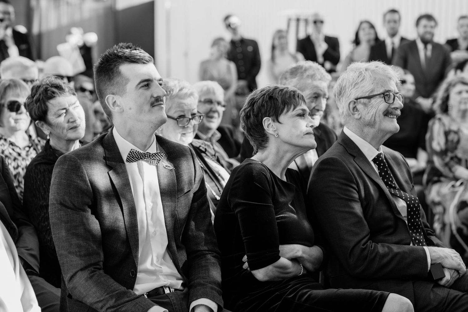 Black and white photo of wedding guests watching the ceremony.