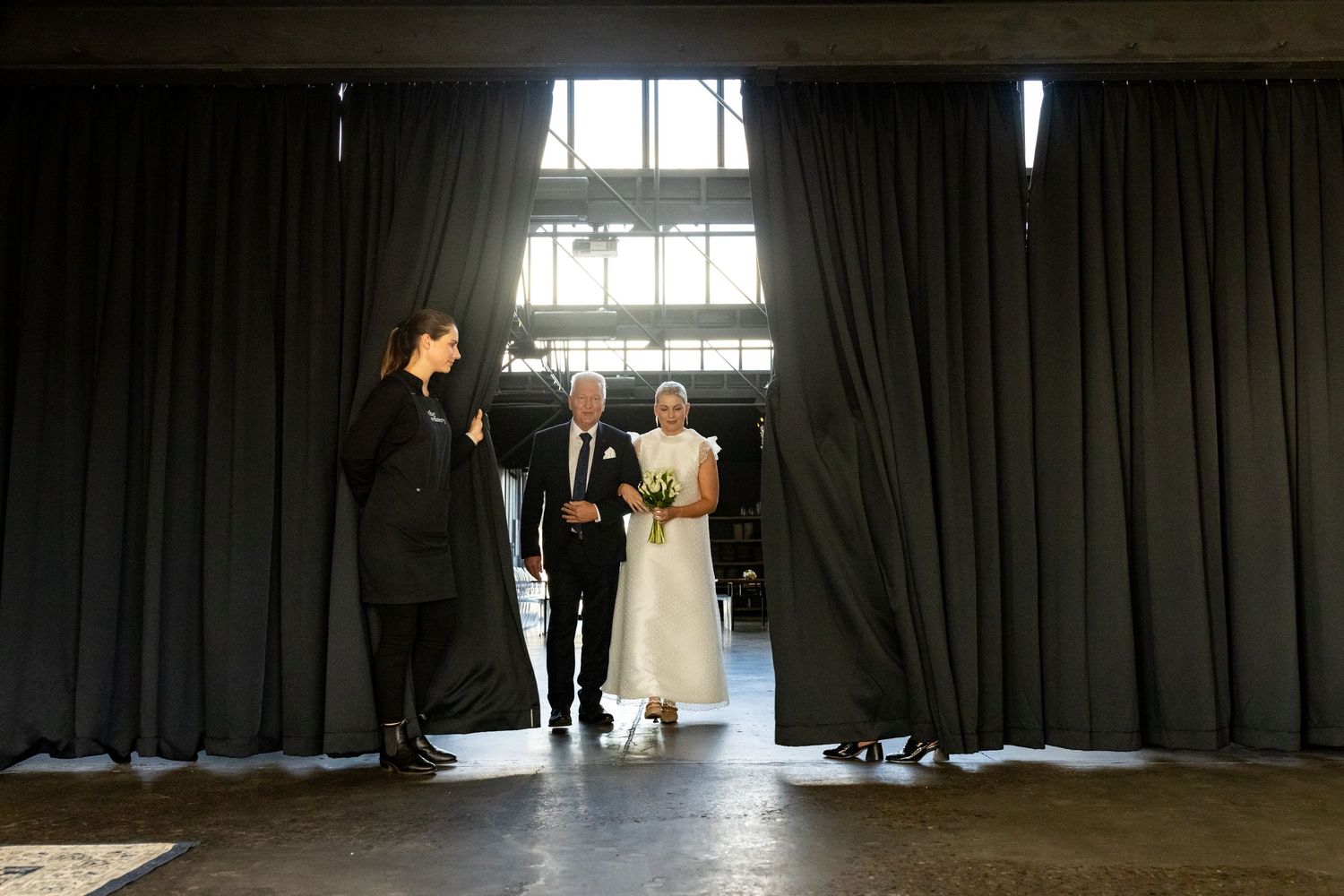 Dramatic silhouettes against bright window during indoor wedding ceremony.